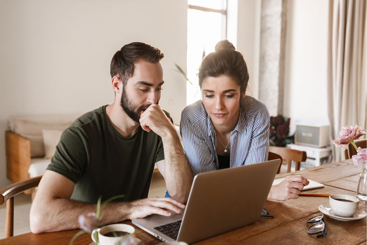 Un homme et une femme regardent ensemble un ordinateur portable à la maison
